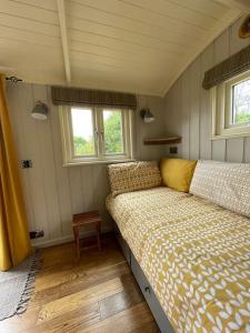a small bedroom with a bed and two windows at Bathsheba, Luxurious Shepherds Hut set in Todber a hamlet set in Thomas Hardy's iconic rural Dorset in Todber