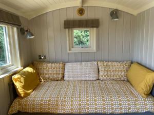 a couch in the corner of a room with two windows at Bathsheba, Luxurious Shepherds Hut set in Todber a hamlet set in Thomas Hardy's iconic rural Dorset in Todber