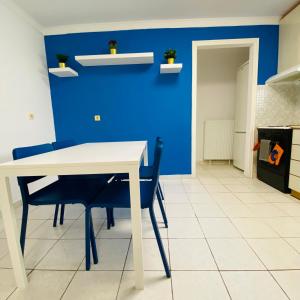 Koker's Place في سلانيك: غرفة طعام مع طاولة بيضاء والجدار الأزرق