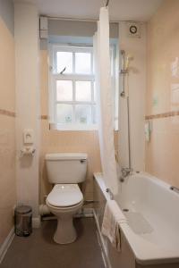baño con aseo, bañera y ventana en Old Grey Mare Inn by Greene King Inns en Hull