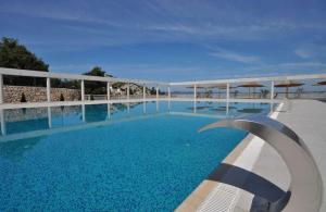 a large swimming pool with blue water and umbrellas at Premium mobile home Maslina - Oaza mira in Drage
