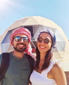 a man and a woman standing in front of a tent at Warm bubbles Wadi Rum in Wadi Rum