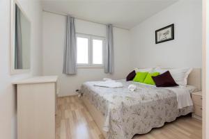 a white bedroom with a bed and a window at Apartments Ana in Brela