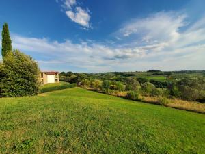 um grande campo verde com uma casa à distância em La Casa nel Borgo 418 con garage em Montespertoli