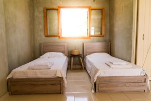 2 camas individuales en una habitación con ventana en Exoristoi Nature Suites, en Gavdos