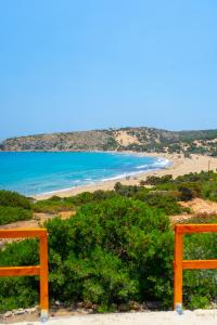 a view of a beach with two orange benches at Exoristoi Nature Suites in Gavdos