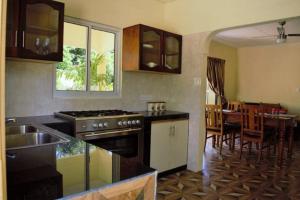 a kitchen with a stove and a dining room at My Ozi Perl New Creole Villas in Grand'Anse Praslin