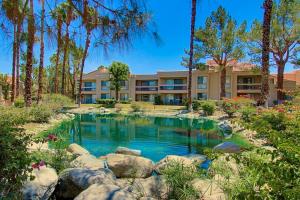 a pool in front of a building with trees at Canyon Shores Getaway in Cathedral City