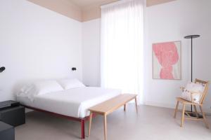 a white bedroom with a bed and a wooden table at Casa Umbertina in La Spezia