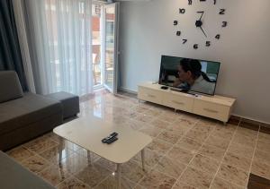 a living room with a tv and a table and a clock at Fishta apartments Q5 35 in Velipojë