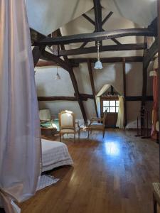 a room with a bed and chairs and a wooden floor at Chambre d'hôtes Saint Jacob Relais de Chasse du XVIII Siècle in Les Fougerêts