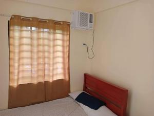 a bedroom with a bed and a window with a air conditioner at Reinhardshausen Suites and Residences- Lovely Air-Conditioned Units in Tuguegarao City