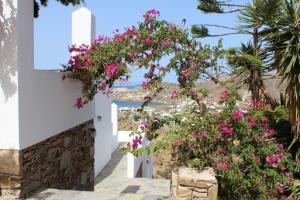 a pathway with pink flowers on a white building at Country House Apartments in Ios Chora