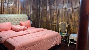 um quarto com uma cama com almofadas cor-de-rosa e uma cadeira em Para para cafe & cottage em Berastagi