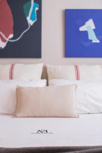 a bed with white sheets and pillows in a room at Apartamentos Martalia Áticos Deluxe in Ronda