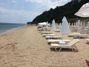 a row of lounge chairs and umbrellas on a beach at Panoramic Sea View Apartment in Byala