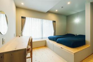 1 dormitorio con cama, escritorio y ventana en 宿 ロイノハコ en Gotsu