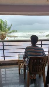 un hombre sentado en una silla mirando hacia el océano en Gokarna Govekar Beach Stay en Gokarn