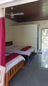 Habitación con 3 camas con almohadas rojas. en Gokarna Govekar Beach Stay en Gokarn