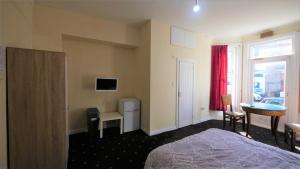 a hotel room with a bed and a desk and a window at Palm Beach Hotel in Bournemouth