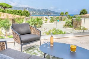 a patio with a table and a chair with wine glasses at Akwabay - Les Villas du Cap in Le Lavandou