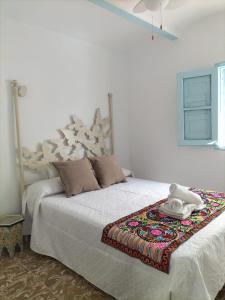 Un dormitorio con una cama blanca con una manta. en La casa de tío Vidal en Pedro Bernardo