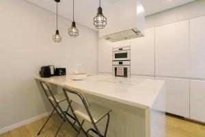 a white kitchen with a counter and chairs at Next to the Trees and the Sea in Estoril