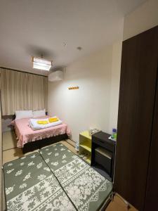 Habitación pequeña con 2 camas y escritorio. en Shinjuku Sky hostel en Tokio