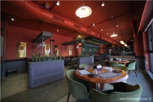a dining room with tables and chairs and red walls at Ibiza Hotel in Ahmedabad