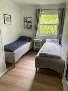 two beds in a room with a window at Leilighet med flott uteplass in Ulefoss