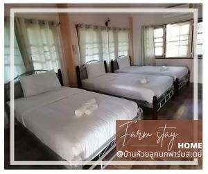 2 camas en una habitación con sábanas y almohadas blancas en บ้านห้วยลูกนกฟาร์มสเตย์ Banhuailuknok Farmstay, en Ratchaburi