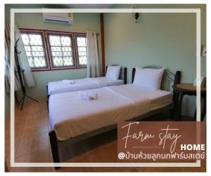 two beds in a room with two windows at บ้านห้วยลูกนกฟาร์มสเตย์ Banhuailuknok Farmstay in Ratchaburi