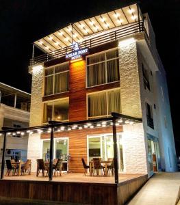 un bâtiment avec une terrasse dotée de tables et de chaises la nuit dans l'établissement ASKAR PORT OTEL, à Tasucu