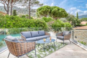 a patio with a couch and two chairs and a table at Akwabay - Les Villas du Cap in Le Lavandou