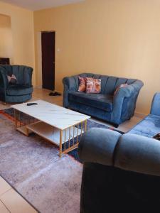 a living room with two couches and a coffee table at Lux Suites Honey Dew Stays Athiriver in Nairobi +3 photos