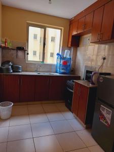 a kitchen with wooden cabinets and a sink and a window at Lux Suites Honey Dew Stays Athiriver in Nairobi