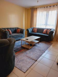 a living room with two couches and a coffee table at Lux Suites Honey Dew Stays Athiriver in Nairobi