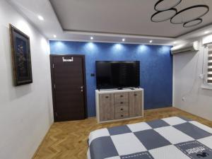 1 dormitorio con TV en una pared azul en Apartman Cipi2, en Sombor