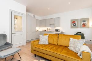 a living room with a yellow couch and a kitchen at ALTIDO Stylish 1 bed flats in Soho, next to Piccadilly Circus in London