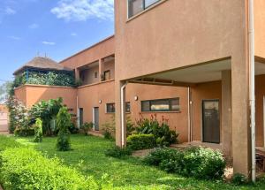 un bâtiment avec une cour verdoyante devant lui dans l'établissement Le Lézard Vert, Maison d'Affair à Niamey, à Niamey