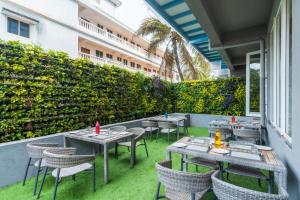 an outdoor patio with tables and chairs and a hedge at De Mandarin Candolim Beach Goa in Candolim