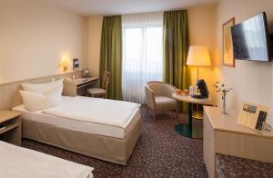 a hotel room with a bed and a desk at AMBER HOTEL Chemnitz Park in Chemnitz