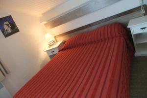 a bedroom with a bed with a red bedspread at H&ocirc;tel U Pozzu in Sisco