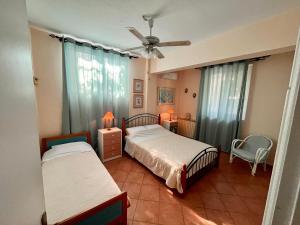 um quarto com 2 camas e uma ventoinha de tecto em Yellow House Oropos em Néa Palátia