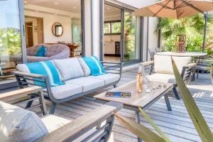 a patio with a couch and chairs and an umbrella at Akwabay - Les Villas du Cap in Le Lavandou