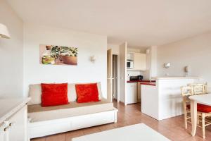 マルモールにあるResidence Pont Royal en Provence - maeva Homeのリビングルーム(赤い枕付)、キッチンが備わります。
