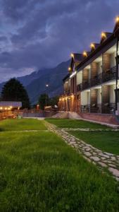 a building with a green field in front of it at Hilltop Kazbegi in Stepantsminda