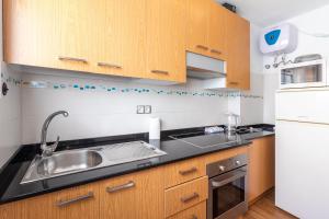 a kitchen with wooden cabinets and a sink at Flatguest Triana urbano in Las Palmas de Gran Canaria
