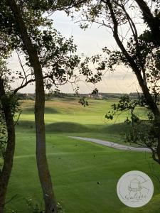 a view of a golf course from behind some trees at Appartement Sealight in De Haan