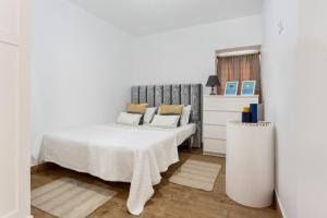 ein weißes Schlafzimmer mit einem Bett und einer Kommode in der Unterkunft ALTIDO Quaint house with Patio in Sintra